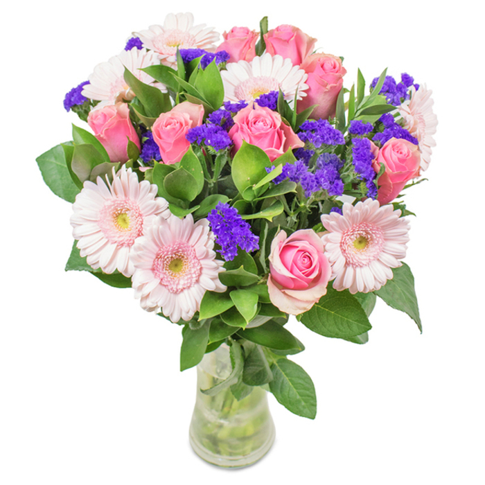 This beautifully structured bouquet, crafted by experienced florists in Purley, features a vibrant palette of pink roses and soft Gerbera daisies, all assembled in a transparent glass vase set against a white backdrop. Count the blooms-seven to nine medium pink roses, petals elegantly coiled or just unfolding, conjure the romance of a quiet afternoon in Rotary Field. Five to seven pale pink Gerbera daisies introduce a subtle grandeur, their large, circular heads and delicate, almost white centers reminiscent of wildflowers glimpsed on the Purley Downs. Interspersed are vivid clusters of purple statice that provide dramatic contrast and a hint of textural intrigue, echoing the lively energy found at the local market. A lush tangle of deep green foliage fills out the base, infusing the whole with freshness and life. The clear vase, showing off the healthy length of stems and sparkling water, suggests the bouquet is freshly delivered and meant to enliven any occasion-from birthdays and anniversaries in Purley to a simple moment of celebration. The entire gift exudes joy, affection, and a connection to the local community.